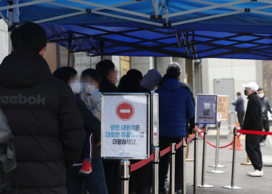 국내 코로나19 신규 확진자 수가 39만5598명을 기록한 24일 오전 서울시내 한 호흡기전담클리닉으로 지정된 병원 앞에 시민들이 코로나 검사를 받기 위해 줄을 서고 있다.  연합뉴스